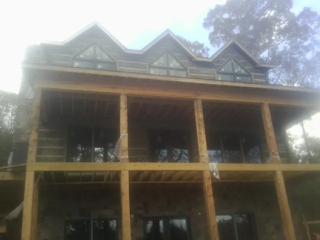 Dormers and porch framing on a large log home under construction — Roof Coating work by our crew in Sharpsville
