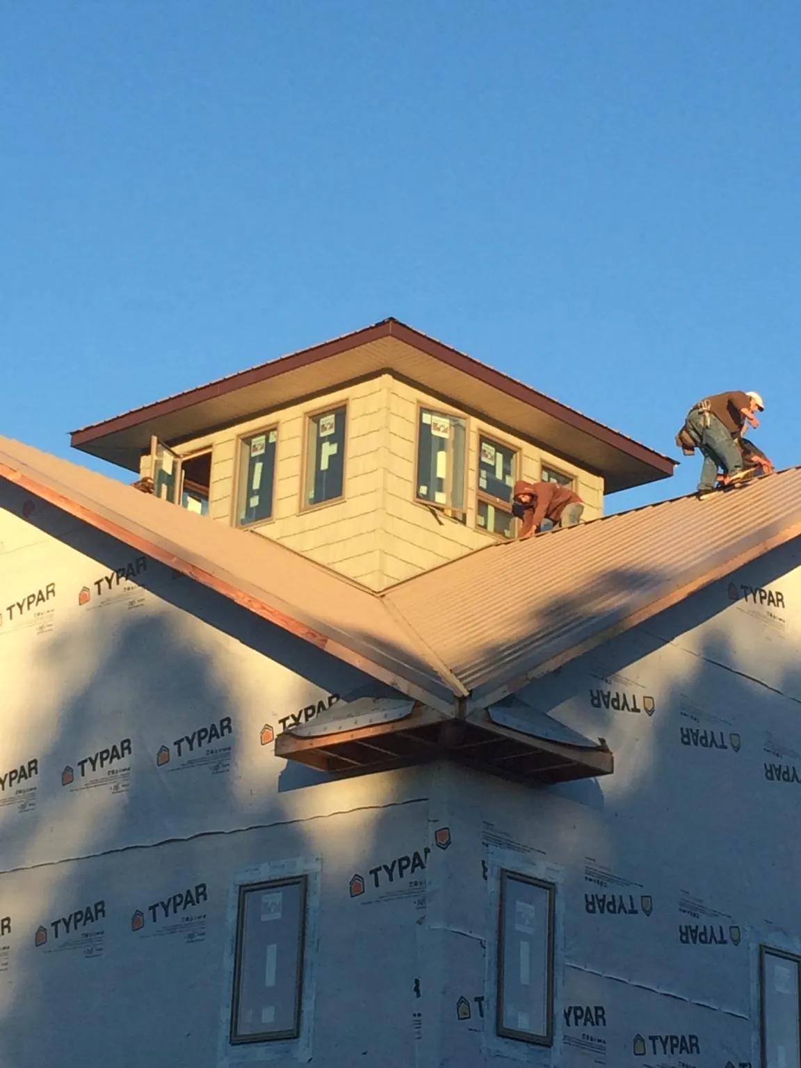 Roofers working around a rooftop cupola on a new metal roof at sunset — Roof Waterproofing in Sharpsville by Roofing Brothers